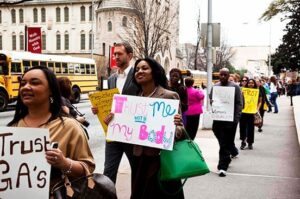 A line of people holding signs in support of reproductive justice outside of the Georgia State Capitol.