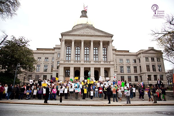 People hold signs outside of the Georgia State Capitol during the Walk in My Shoes Rally in 2012.