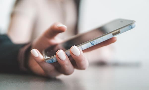 A model holding a cell phone in hand to call for an appointment.