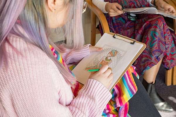 A model posing as a patient colors a picture while sitting in the clinic waiting area.