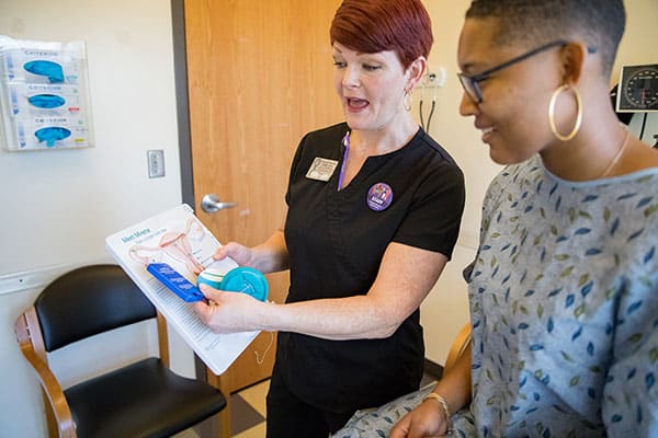 Staff member shows a model posing as a patient information about birth control options.