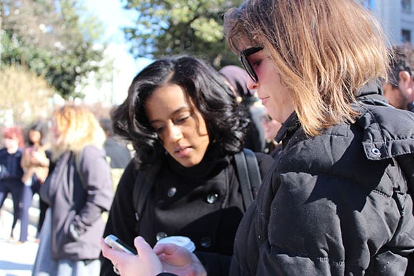 A staff member shows an intern something on their phone at an outdoor rally.