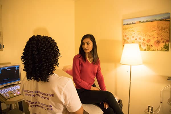 A clinic staffer speaks with a model posing as a patient.