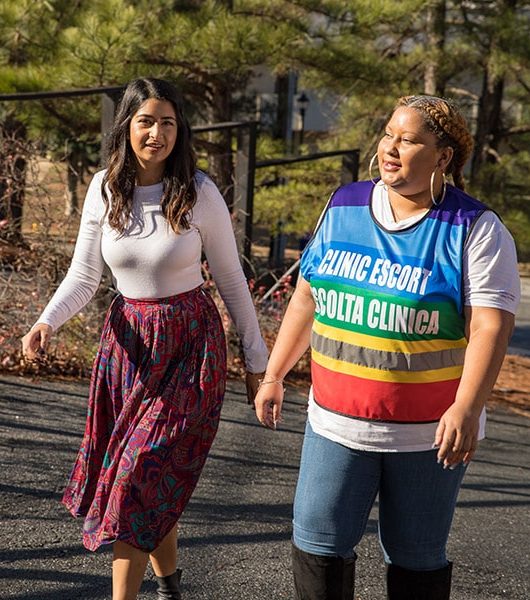 Model poses as a patient walking through the clinic parking lot with a clinic escort.
