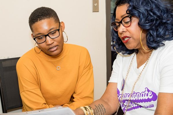 A clinic staff member shows education materials to a model posing as a patient.
