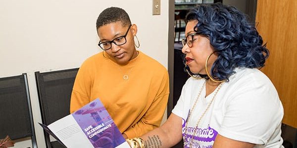 A clinic staffer presents a pamphlet to a model posing as a patient.