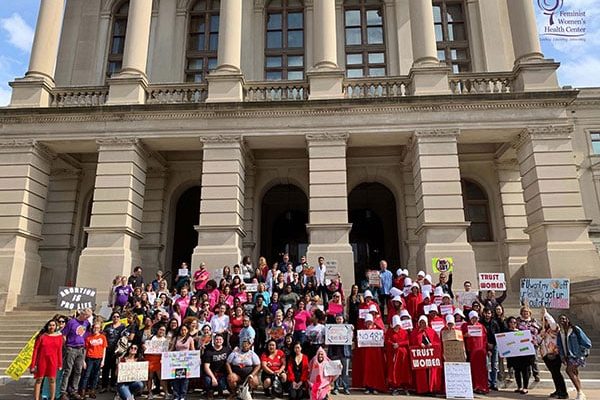 People hold signs outside of the Georgia State Capitol during the rally against HB 481 in 2019.