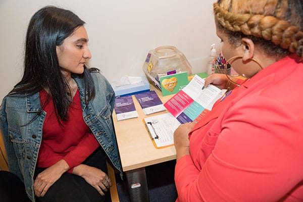 A clinic staffer presents a pamphlet to a model posing as a patient.